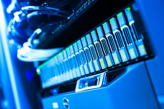 Home A detailed view of a blue lit computer server rack in a data center showcasing technology and hardware.